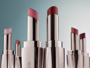 Kategoriebild Lippenpflege von La Mer: Mehrere Lippenstifte in silbernen Hülsen sind nebeneinander aufgestellt, vor neutralem hellblauem Hintergrund.